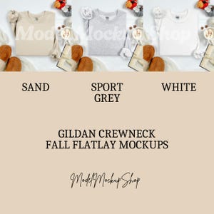 May include: Three Gildan crewneck sweatshirts in sand, sport grey, and white are displayed in a flatlay mockup. The sweatshirts are surrounded by fall-themed decor, including a book, a coffee cup, and autumn leaves. The text "GILDAN CREWNECK FALL FLATLAY MOCKUPS" is visible.