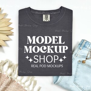 Może przedstawiać: Szary t-shirt z nadrukiem w kolorze białym, na którym widnieje napis "MODEL MOCKUP SHOP" i "REAL POD MOCKUPS".