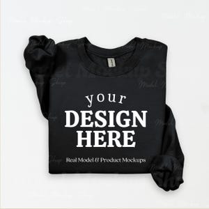 May include: Black crewneck sweatshirt with the text "your DESIGN HERE" in white. The sweatshirt is a mockup, perfect for showcasing custom designs. The sleeves are folded, and the garment is displayed on a white background.