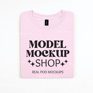 Könnte beinhalten: Ein pinkfarbenes T-Shirt mit dem Text "MODEL MOCKUP SHOP" und den Worten "REAL POD MOCKUPS" darauf gedruckt.