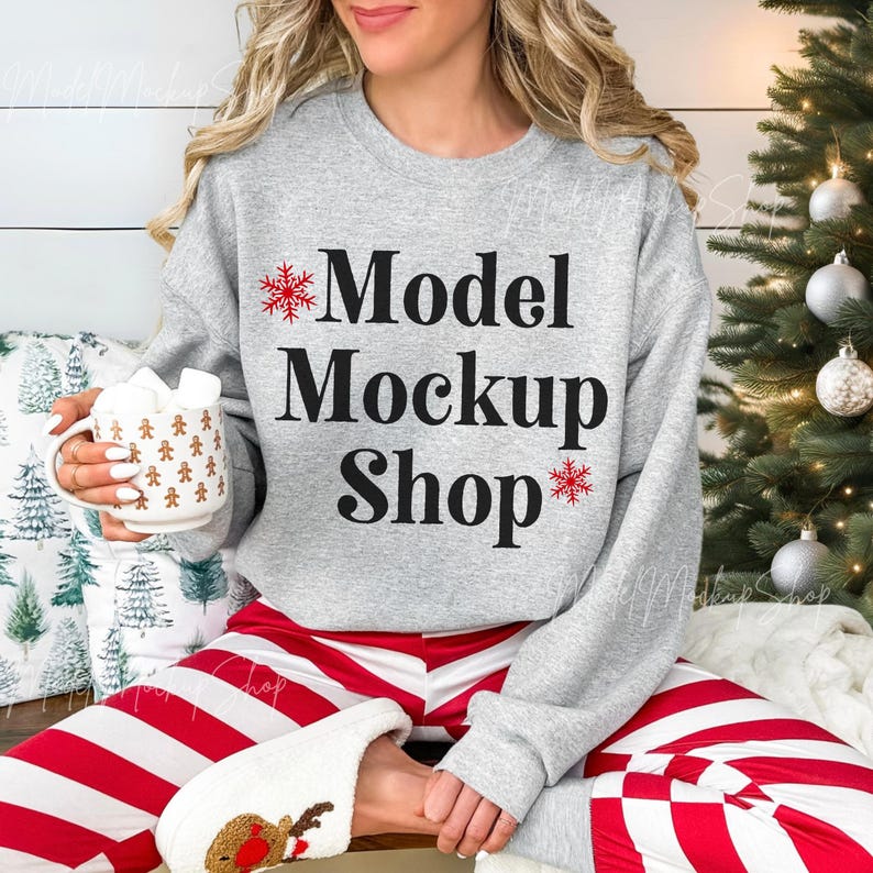 May include: A gray sweatshirt with the text "Model Mockup Shop" and red snowflake designs. The model is wearing red and white striped pants and white fuzzy slippers.