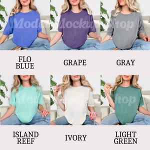 May include: A collection of six short-sleeved t-shirts in various colors: Flo Blue, Grape, Gray, Island Reef, Ivory, and Light Green. Each shirt is displayed on a person. The names of the colors are printed below each shirt.