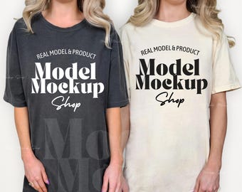 May include: Two women wearing oversized t-shirts. The shirt on the left is dark gray with the text "REAL MODEL & PRODUCT Model Mockup Shop" printed in white. The shirt on the right is cream colored with the text "REAL MODEL & PRODUCT Model Mockup Shop" printed in black.