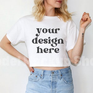 May include: A white cropped t-shirt with the text "your design here" printed in black.