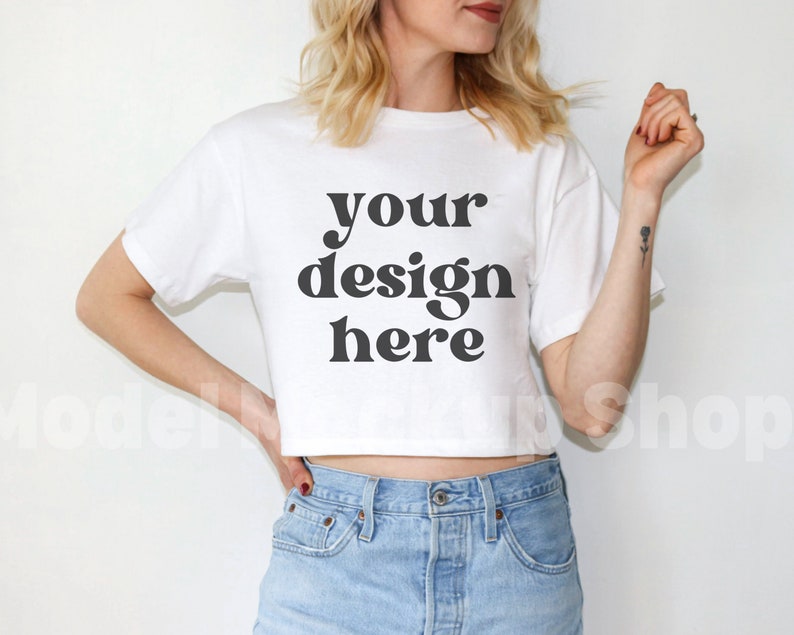 May include: A white cropped t-shirt with the text "your design here" printed in black.