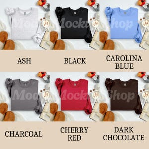 May include: A collection of six crewneck sweatshirts in various colors: ash, black, Carolina blue, charcoal, cherry red, and dark chocolate. Each sweatshirt is displayed with a cozy fall theme.