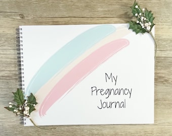 May include: A white spiral bound journal with a pink and blue watercolor design and the text "My Pregnancy Journal".