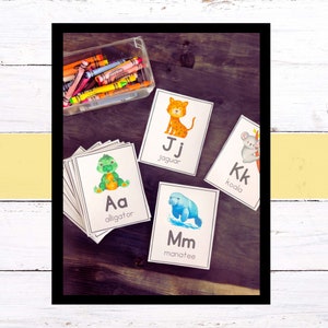 May include: A set of alphabet flash cards featuring animals. Each card has a letter, animal name, and a colorful illustration of the animal. The animals include an alligator, jaguar, koala, and manatee.
