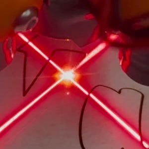 May include: A bright red laser beam crosses over the letters "VC" drawn on a white surface. The laser's light source is a bright, central point. The letters are outlined in black.