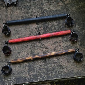 Beautiful and brutal handmade leather cuffs with spreader bar.