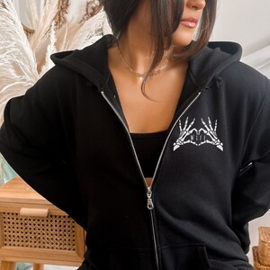 May include: Black zip-up hoodie with a white skeleton hand design that says "I love my wife".