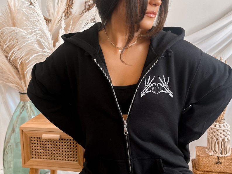 May include: Black zip-up hoodie with a white skeleton hand design that says "I love my wife".
