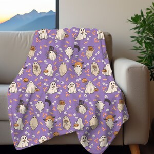 May include: Purple fleece throw blanket with a repeating pattern of white ghosts, orange pumpkins, and candy corn. The ghosts are holding pumpkins and sweets.