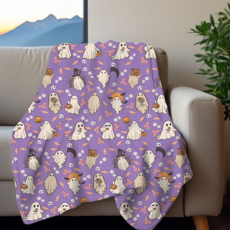 May include: Purple fleece throw blanket with a repeating pattern of white ghosts, orange pumpkins, and candy corn. The ghosts are holding pumpkins and sweets.