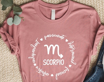 以下が含まれることがあります： ダスティローズのTシャツに、白い円形のグラフィックがプリントされています。グラフィックには、蠍座の星座記号と、「蠍座」、「情熱的」、「決意に満ちた」、「集中力がある」、「独立した」、「直感的な」という文字が書かれています。