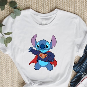May include: White t-shirt with a blue Stitch character wearing a red Superman cape and a blue and red Superman suit.