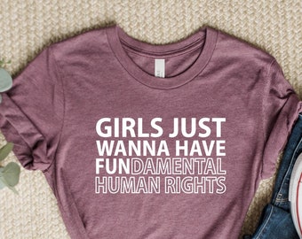 Peut inclure: Un t-shirt mauve avec le texte "Girls Just Wanna Have Fundamental Human Rights" imprimé en blanc.