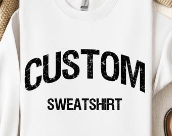May include: White sweatshirt with the text "CUSTOM SWEATSHIRT" in black distressed lettering.
