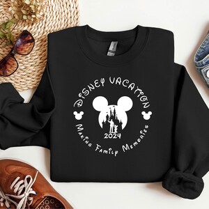 May include: Black sweatshirt with a white circle design featuring Mickey Mouse ears, a silhouette of Cinderella's castle, and the text "Disney Vacation Making Family Memories 2024".