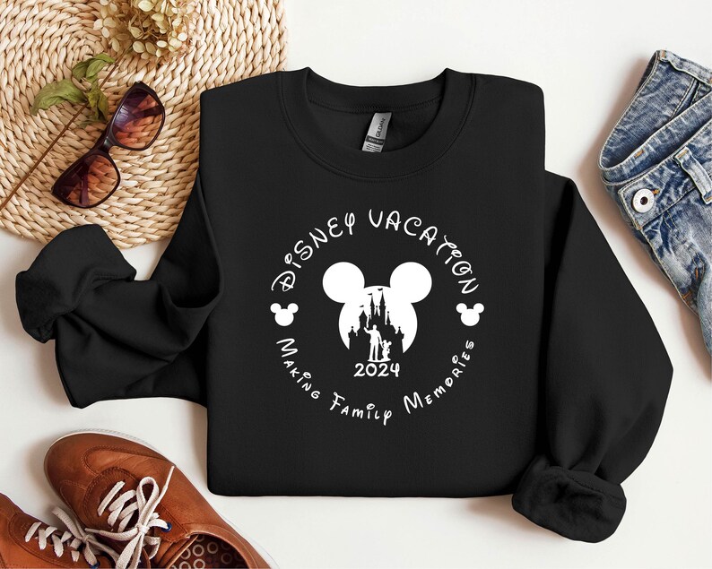 May include: Black sweatshirt with a white circle design featuring Mickey Mouse ears, a silhouette of Cinderella's castle, and the text "Disney Vacation Making Family Memories 2024".