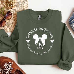 May include: A green sweatshirt with a white circle design featuring a Mickey Mouse head silhouette, a castle, and the text "Disney Vacation Making Family Memories 2024".