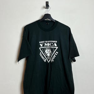 Könnte beinhalten: Ein dunkelgrünes T-Shirt mit einem weißen Dreieckslogo, auf dem "West Hartford YMCA" und "Youth Sports" steht, mit einem Basketball, einem Fußball und einem Baseball im Dreieck.
