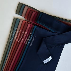 May include: A collection of 10 different colored fabric swatches, arranged in a row from lightest to darkest. The swatches are labeled with their color names and corresponding numbers. The colors are: Haki 41, Teal Mint Blue 44, Caramel 48, Cinnamon 54, Mahogany 56, Dusty Rose 59, Maroon 62, Coffee Brown 68, Petrol Blue 71, and Navy Blue 72.