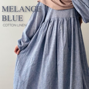 May include: A long-sleeved, loose-fitting dress in a melange blue cotton linen fabric. The garment features a gathered waistline and long sleeves with elasticated cuffs. The text MELANGE BLUE COTTON LINEN is printed on the left side of the image.