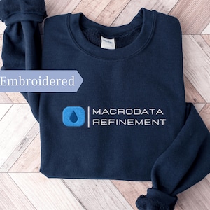 May include: Navy blue embroidered sweatshirt featuring the text "MACRODATA REFINEMENT" in white. The design includes a blue water droplet inside a blue square. The word "Embroidered" is also visible.