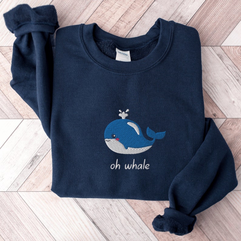 May include: A navy blue sweatshirt with a white embroidered whale and the text "oh whale" on the front.