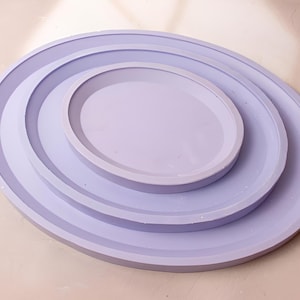 May include: Three concentric, round, lavender-coloured trays, with the smallest tray in the centre.
