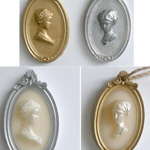 May include: Four oval-shaped wall decor pieces with ornate gold and silver frames. Each frame features a raised, white, plaster bust of a woman in profile.