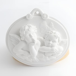 May include: White ceramic ornament featuring two cherubs, one with a finger to its lips and the other with its arms crossed. The ornament has a loop for hanging.