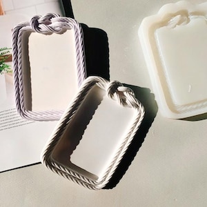 May include: Two white resin tray moulds with rope detailing. The moulds are rectangular and have a raised edge.