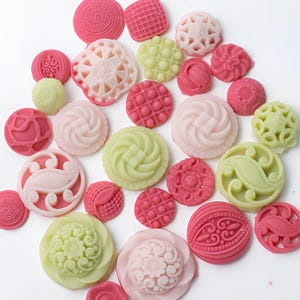 May include: Assortment of decorative buttons in pink, green, and white with various intricate designs.