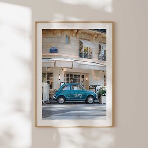 May include: A teal blue vintage Fiat car parked in front of a building with a white awning. The car has the word "Palmg" written on the side.