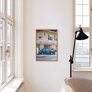 May include: A framed photograph of a blue vintage car parked in front of a building with a white awning. The car has the word "LOVE" written on the side. The building has a sign that says "Le Cafe".