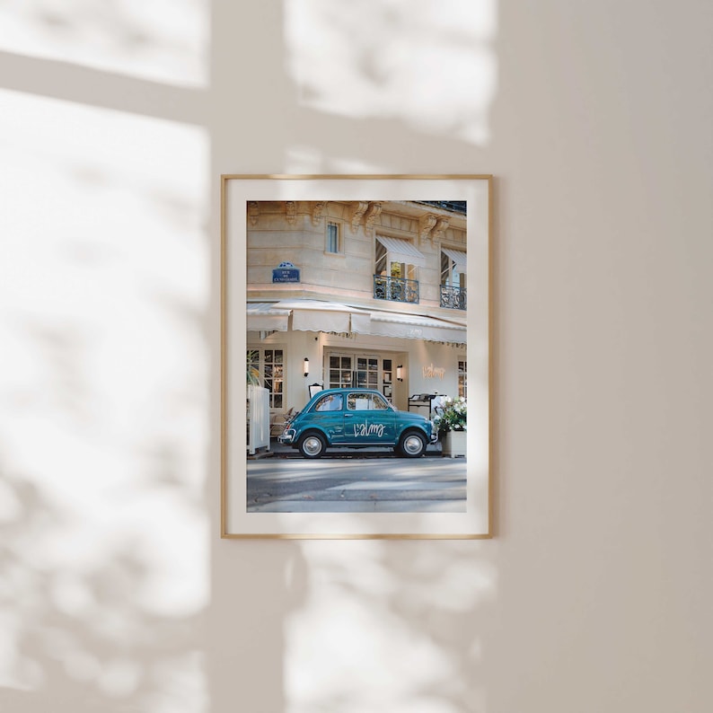 May include: A teal blue vintage Fiat car parked in front of a building with a white awning. The car has the word "Palmg" written on the side.