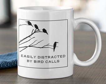 May include: White ceramic mug with a black silhouette of birds on a branch. The mug reads "Easily Distracted by Bird Calls".