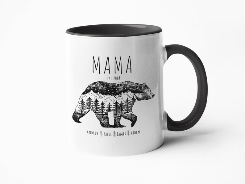 May include: White ceramic mug with a black rim and handle. The mug features a black and white illustration of a bear with mountains and trees inside its silhouette. The text "MAMA EST 2008" is printed above the bear and the names "ANDREW HALLE JAMES AIDEN" are printed below the bear.