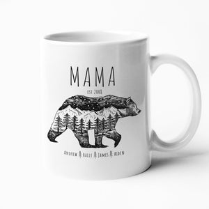 May include: White ceramic mug with a black and white illustration of a bear with mountains and trees inside its silhouette. The text "MAMA EST. 2000" is above the bear and the text "ANDREW HALLE JAMES AIDEN" is below the bear.
