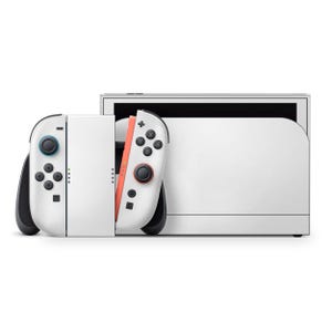 Peut inclure: Une console de jeu blanche avec des manettes détachables. Les manettes sont blanches avec des accents noirs et corail. La console possède un écran et une station d'accueil. Les manettes ont des boutons et des joysticks.