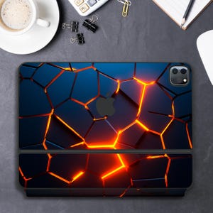 Pode incluir: Uma capa de telefone preta com um design geométrico rachado em tons de laranja e azul. A capa tem uma protuberância de câmera elevada e um logotipo da Apple preto.