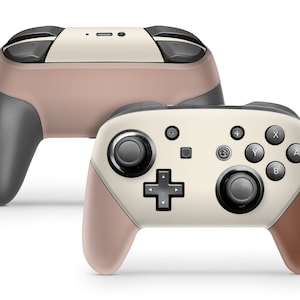 Peut inclure: Deux manettes de jeu sans fil aux couleurs neutres. Les manettes présentent un dessus crème, un corps marron clair et des poignées gris foncé. Les boutons et les joysticks sont noirs. Les manettes sont conçues pour le jeu.