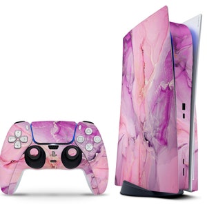 Könnte beinhalten: Eine pinkfarbene und violette Konsole und ein Controller mit Marmormuster für ein Videospielsystem.
