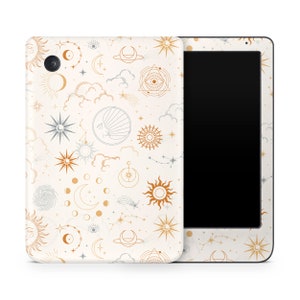 Può includere: Una custodia per tablet bianca con un motivo celeste che presenta soli, lune, stelle e nuvole in oro e argento. La custodia è progettata per adattarsi a un tablet con uno schermo nero.