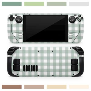 May include: A handheld games console featuring a green and white gingham design. The device has a black screen, black control buttons, and black grips. The top and bottom of the console are visible.