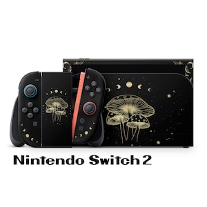 Peut inclure: Console Nintendo Switch 2 noire avec des manettes assorties. La console et les manettes présentent un motif de champignons dorés et des accents célestes. Les manettes ont des boutons bleus et corail. Le texte "Nintendo Switch 2" est en bas.