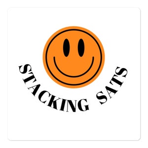 Puede incluir: Cara sonriente naranja con el texto "STACKING SATS" alrededor.