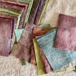 Peut inclure: Un ensemble de carrés de papier faits à la main de différentes couleurs, notamment des nuances de rose, de vert et de marron. Le papier a un aspect texturé et est disposé en piles et dispersé. Vue rapprochée.